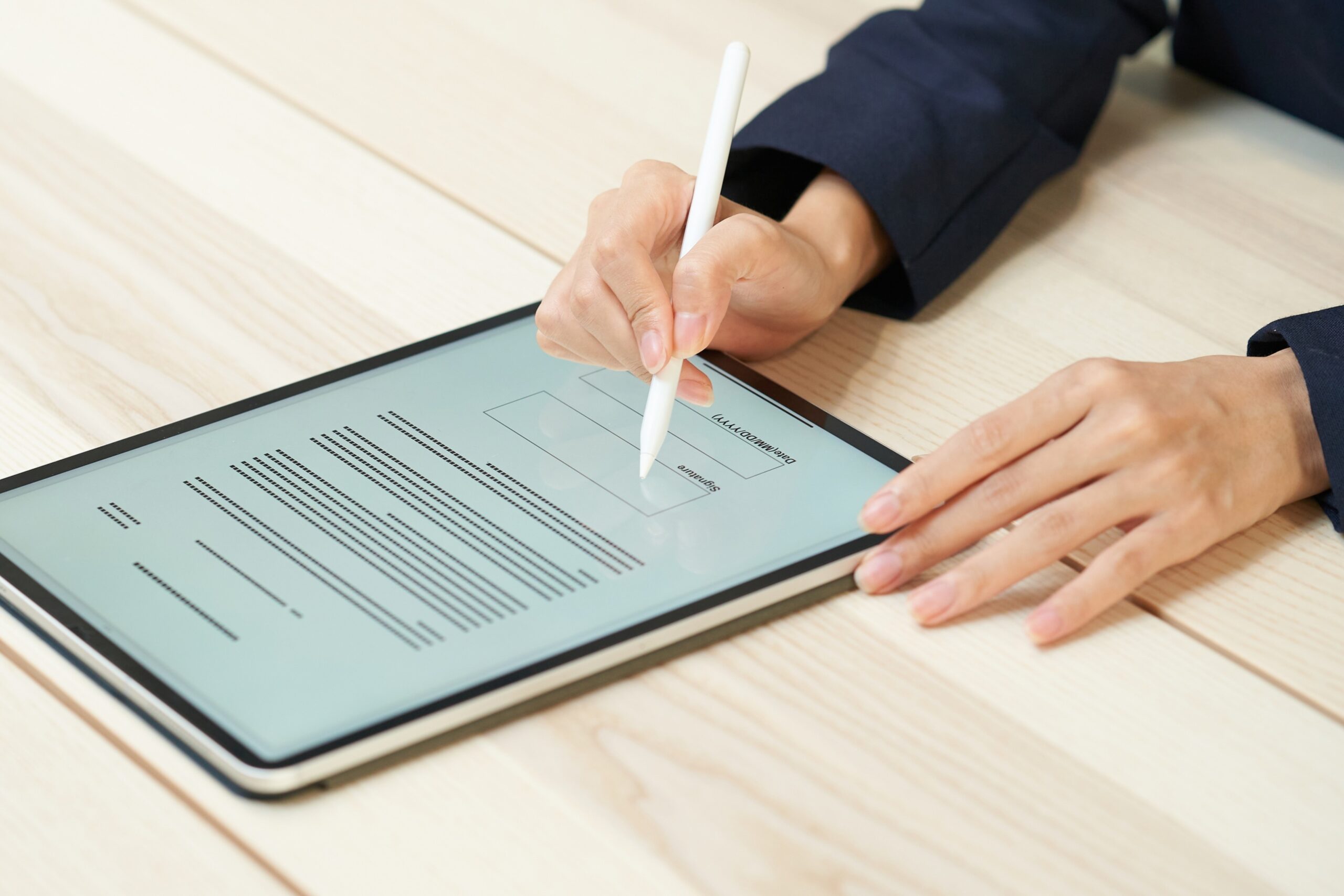 Person using white stylus pen to sign digital document on tablet screen, with signature field visible on the eSignature form displayed on the device