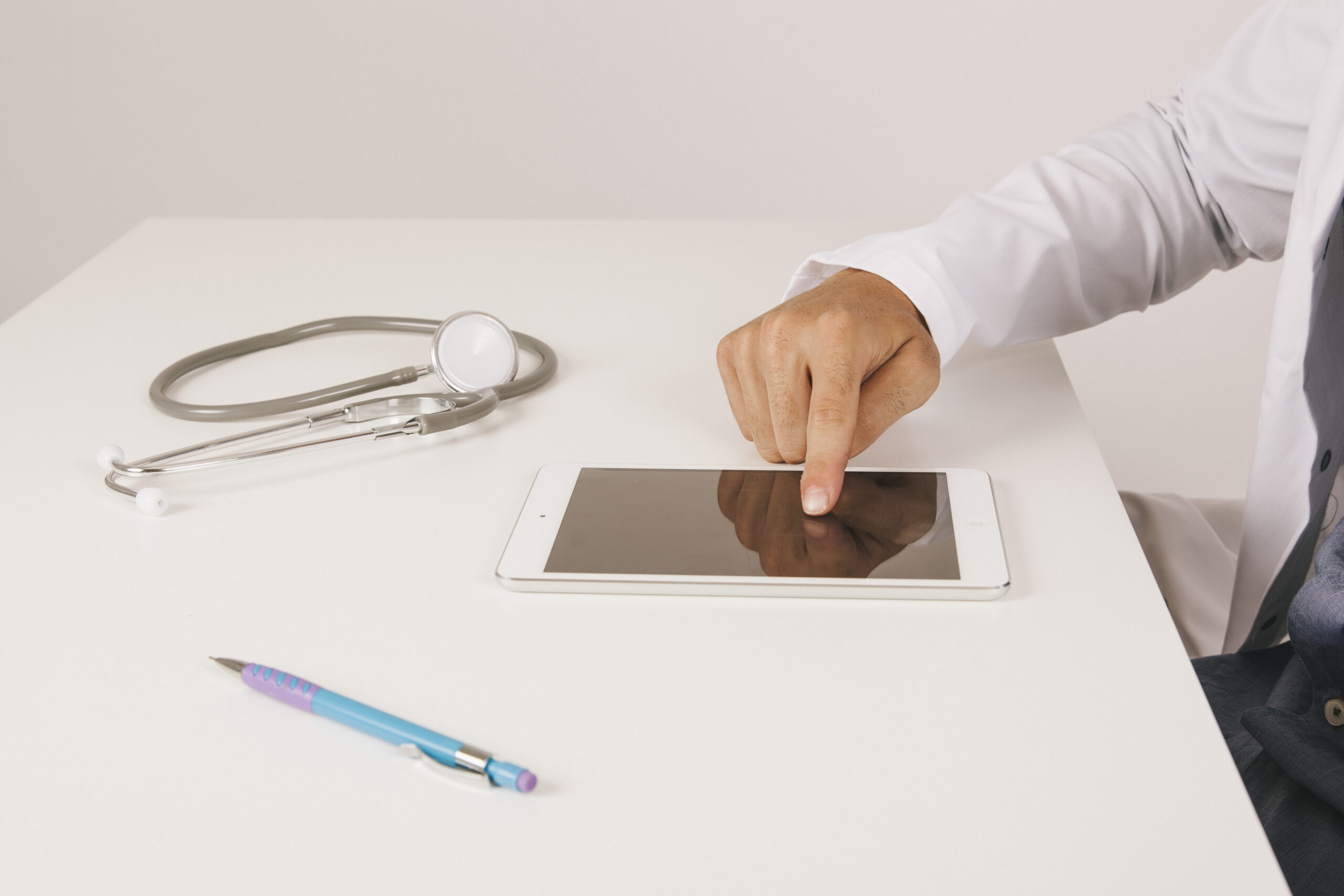Medical practitioner reviewing patient information on a tablet using Electronic Signature for Healthcare, enabled by esignature online free tools and the best esignature software.