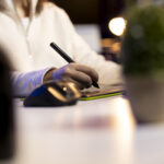 Individual using a digital pad and stylus to create e-signature online, demonstrating modern electronic signatures for secure digital workflows.