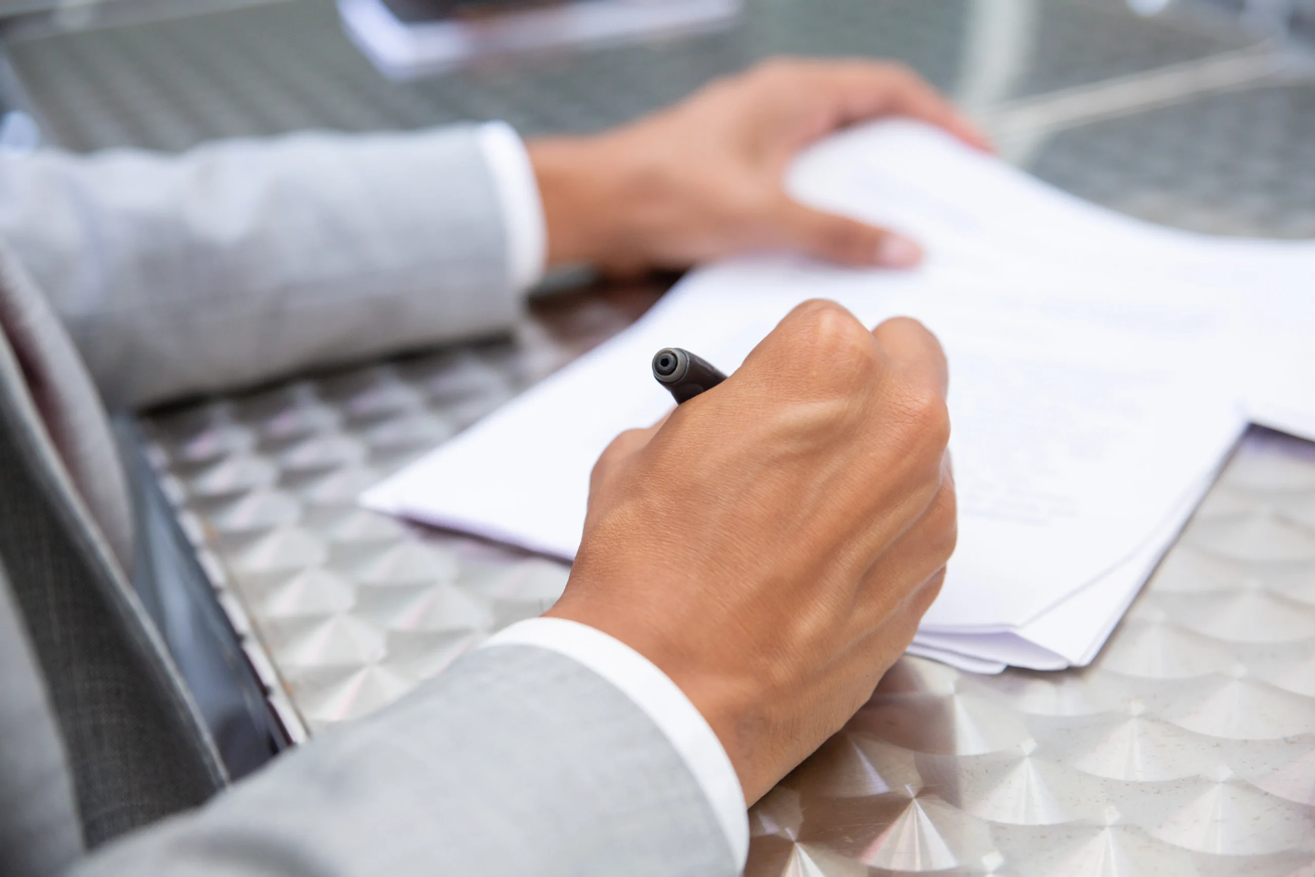 Professional signing a paper document at a desk, illustrating the transition from traditional signing to Electronic Signature Apps and secure digital signature solutions.
