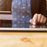 A person using a tablet and holding a credit card, representing the financial efficiency and digital transformation brought by eSignatures in banking and insurance sectors.