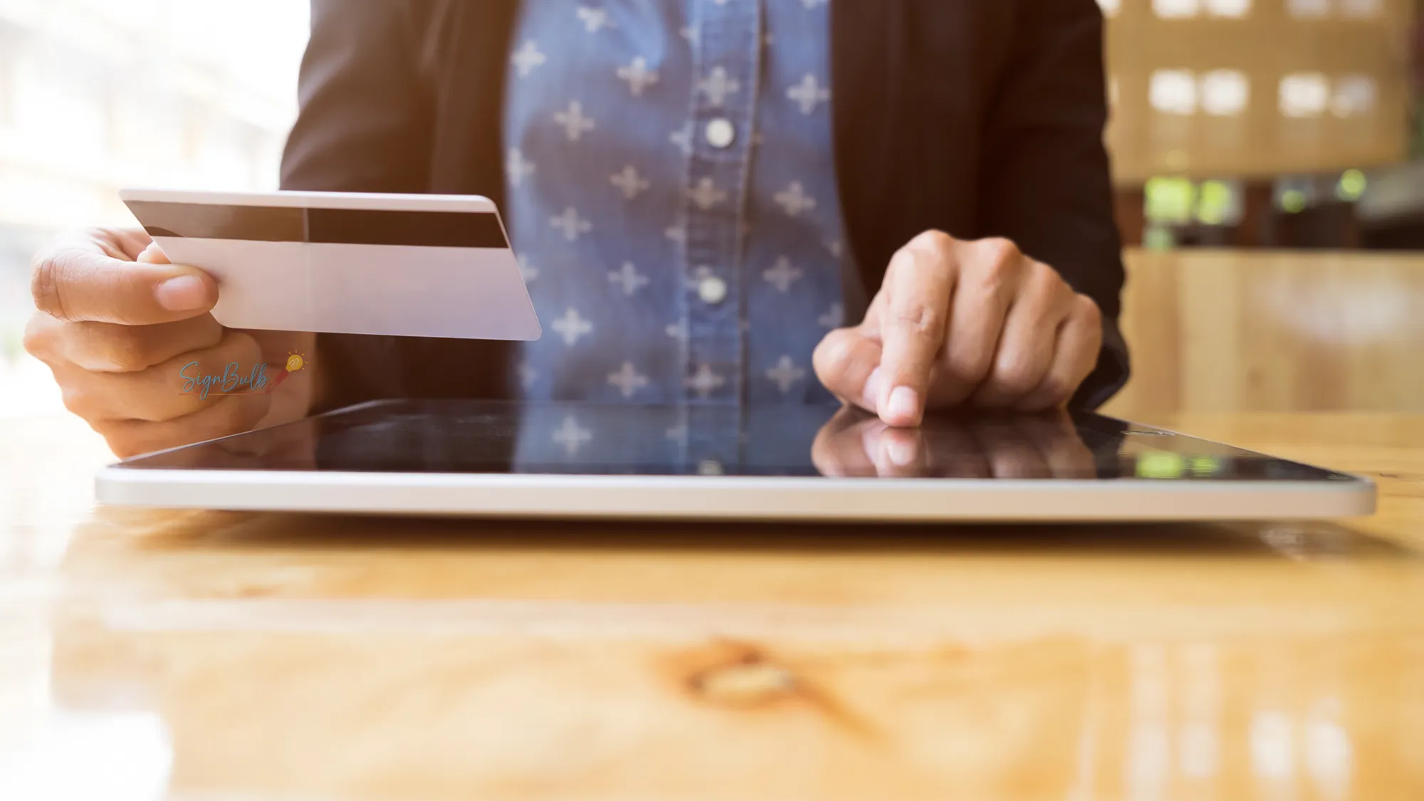A person using a tablet and holding a credit card, representing the financial efficiency and digital transformation brought by eSignatures in banking and insurance sectors.