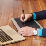 Business professional creating an e-signature on a digital pad connected to a laptop, highlighting an efficient e-signature solution for online agreements.