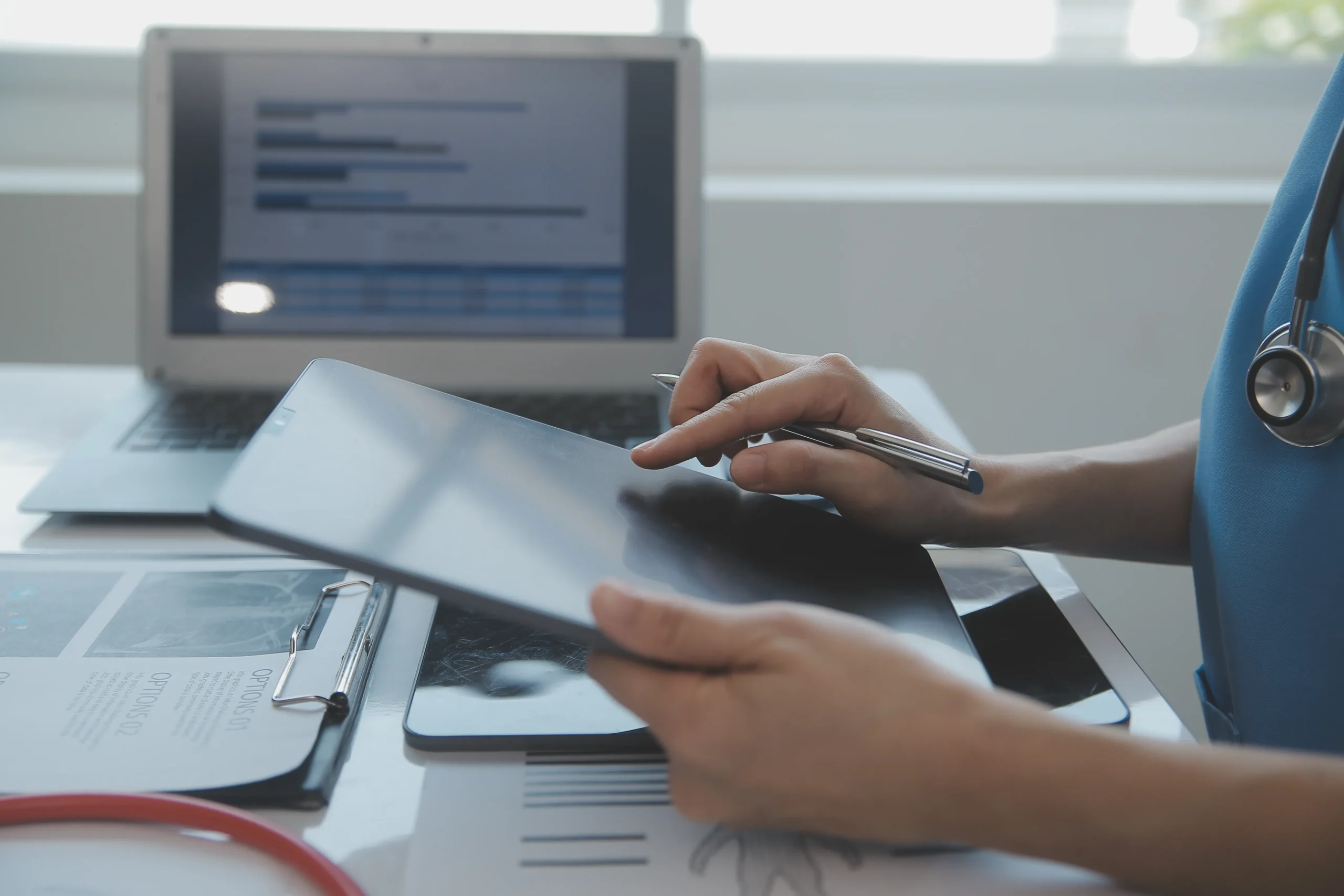 A doctor using a tablet and laptop for a secure e signature for healthcare to create a paperless hospital workflow.