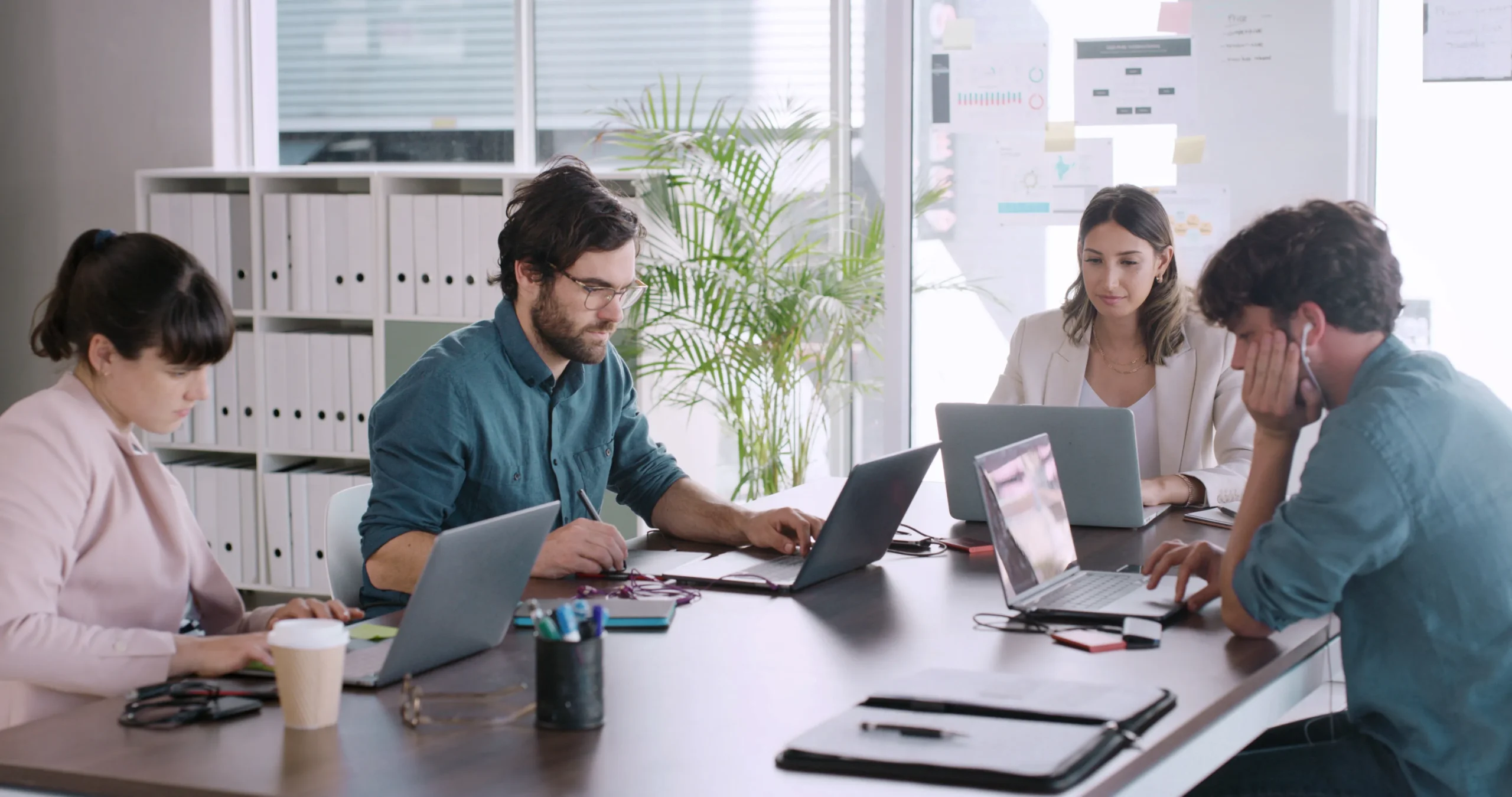An office team working on laptops, managing workflows for electronic signature compliance and maintaining an audit trail.