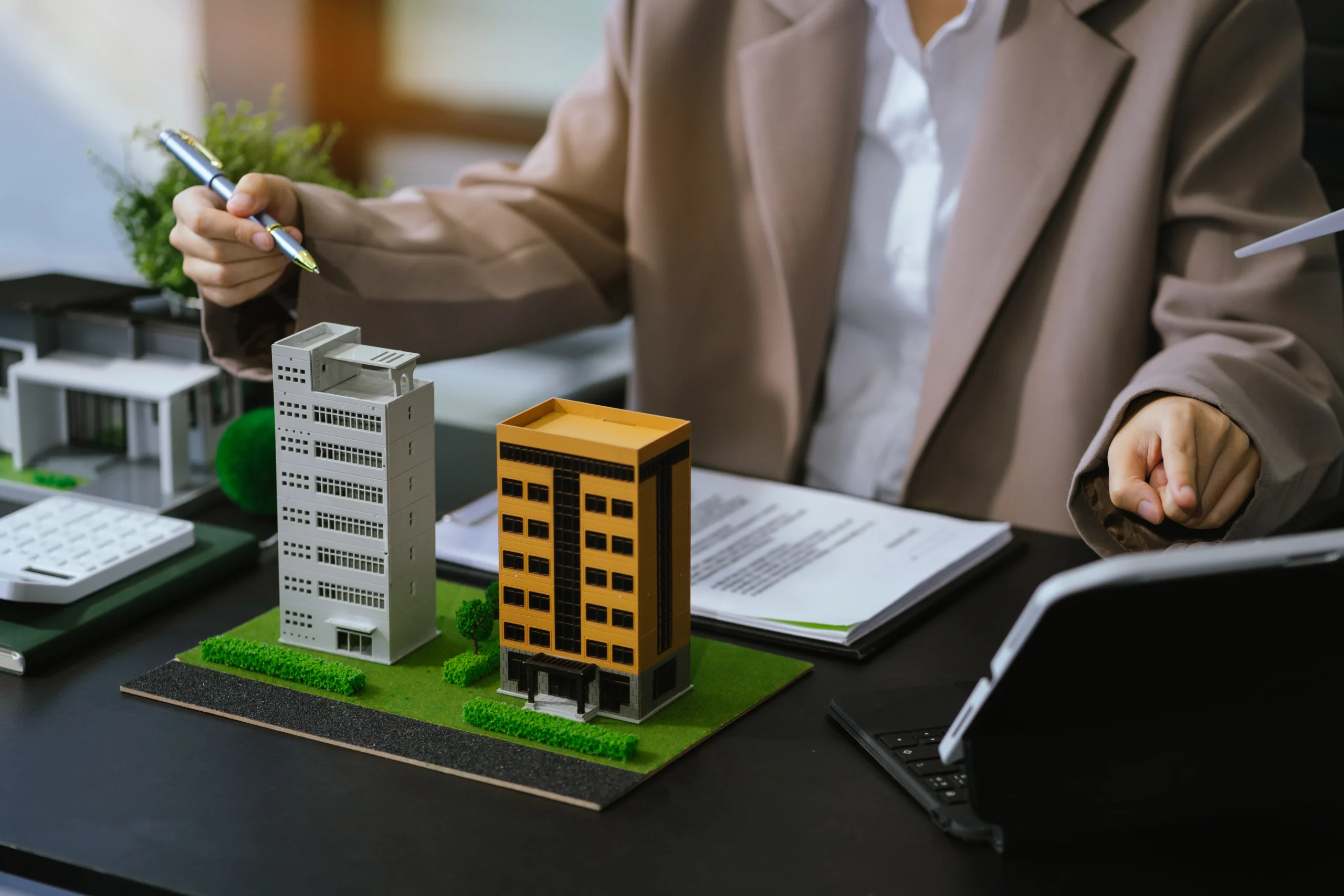 A property manager reviewing contracts alongside building models, utilizing real estate eSignature software to streamline real estate document signing.