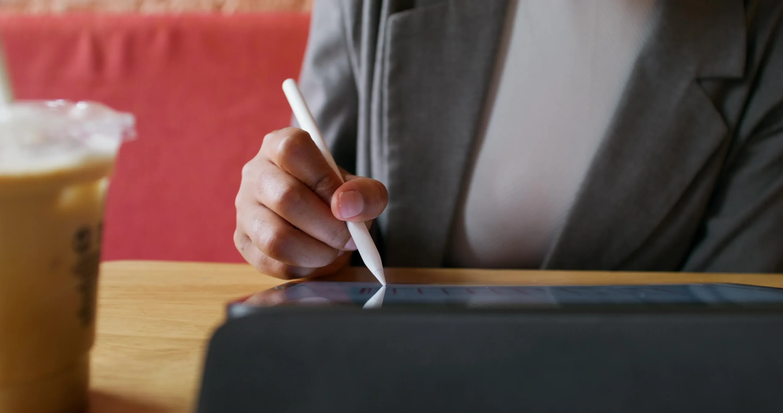 A professional in a blazer signing an electronic contract on a tablet using a digital pen, highlighting efficient online document signing and paperless business solutions.