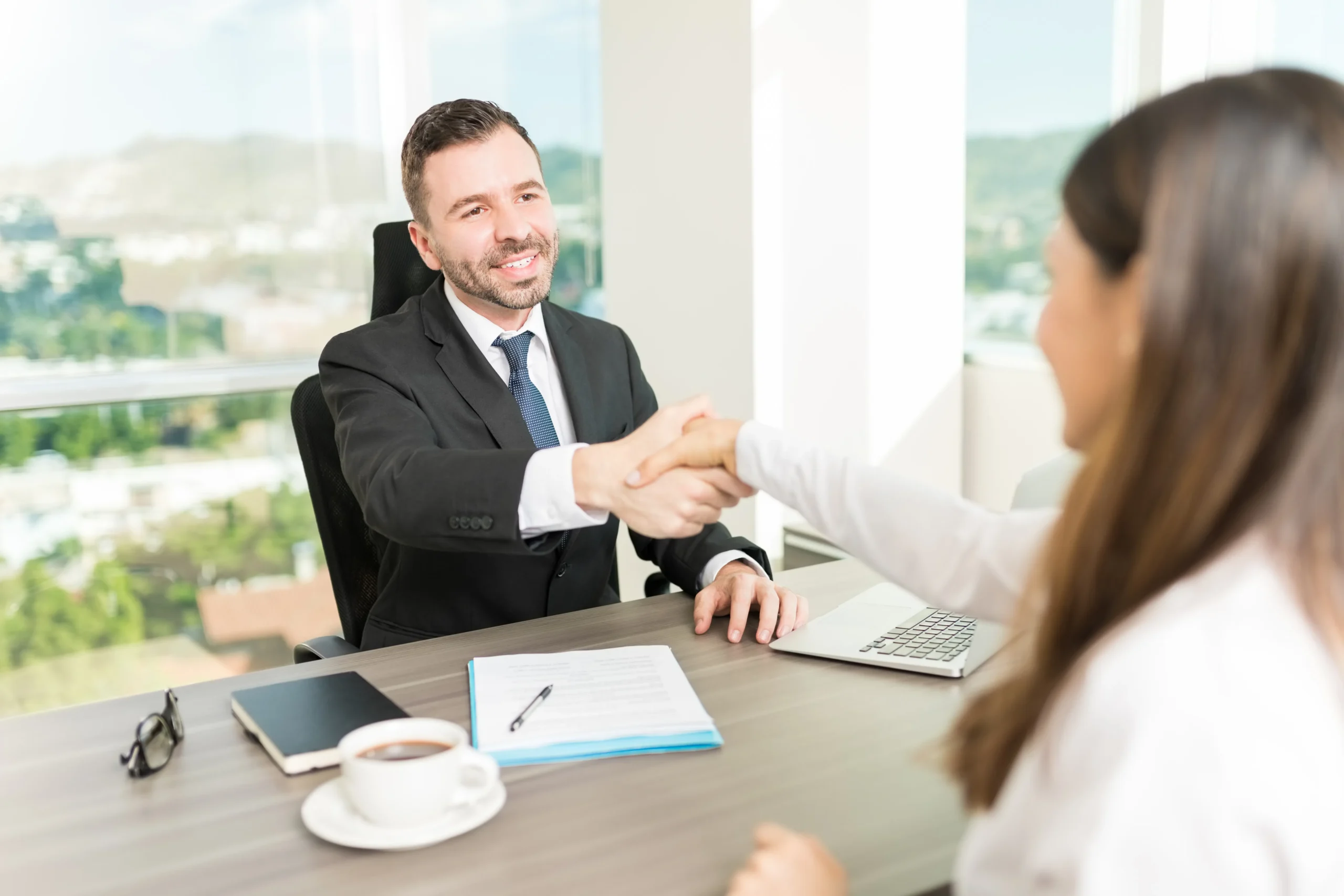 Smiling business professionals shaking hands after using contract signing software to close a deal.