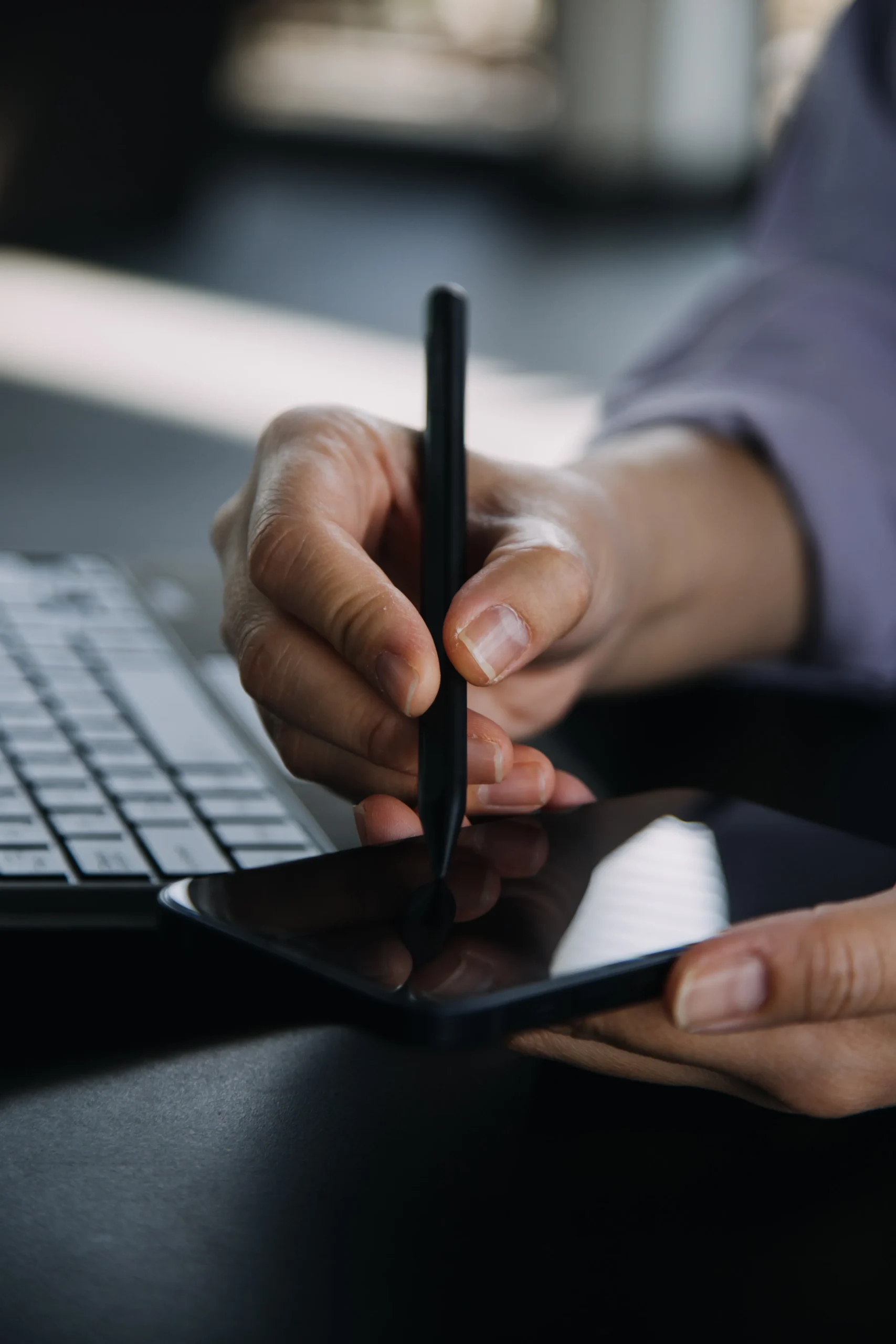 A professional signing a document with a traditional pen next to a laptop, highlighting the shift toward modern e signature solutions.
