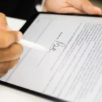 A person signing an onboarding document digitally on a tablet with a stylus, using secure electronic signatures.