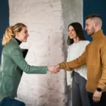 A smiling event manager shaking hands with clients after completing a contract, highlighting how an eSignature for event management streamlines the booking process.