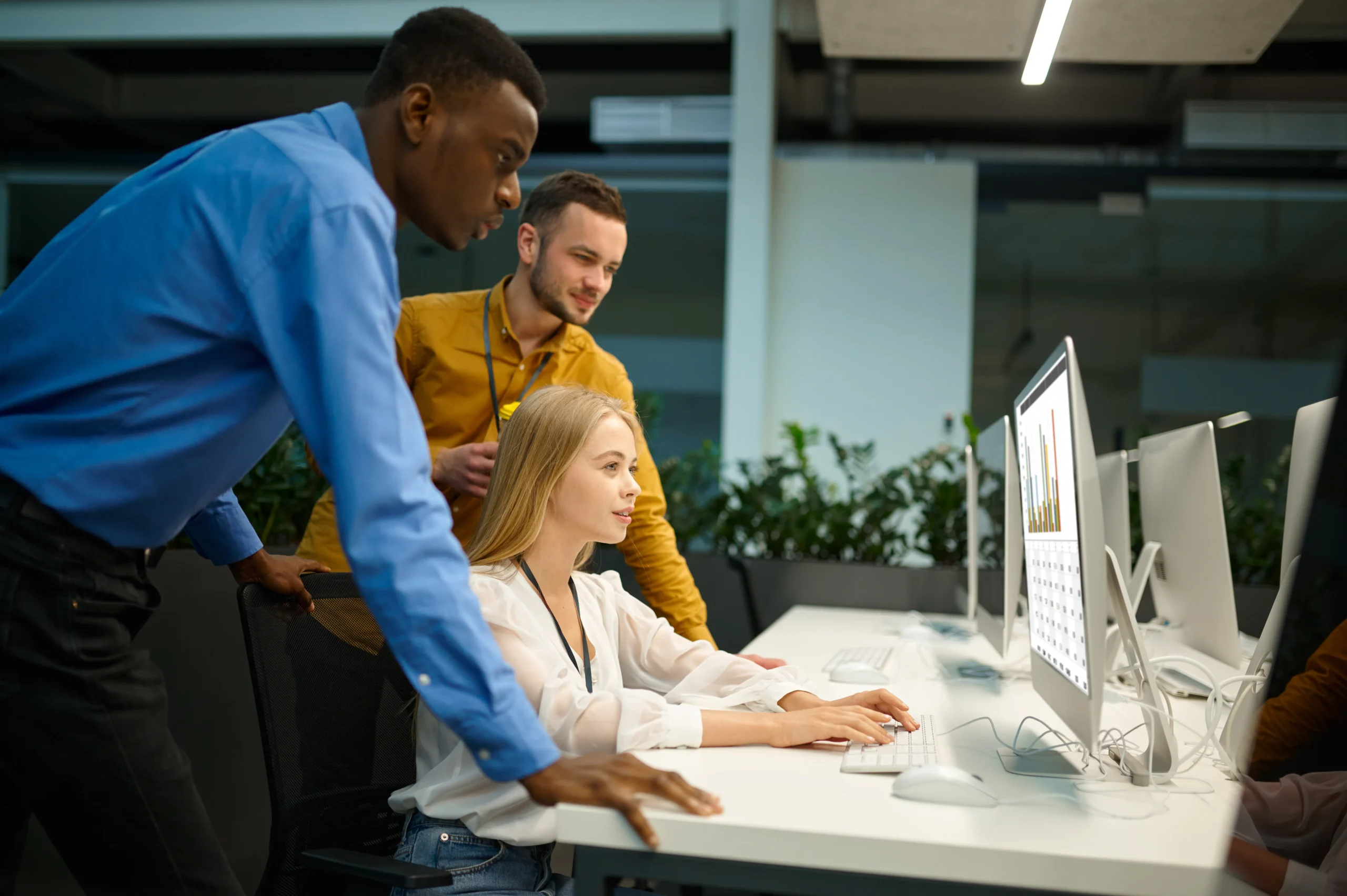 A business team standing around a computer monitor, reviewing analytics integrated with electronic signature software for sales.