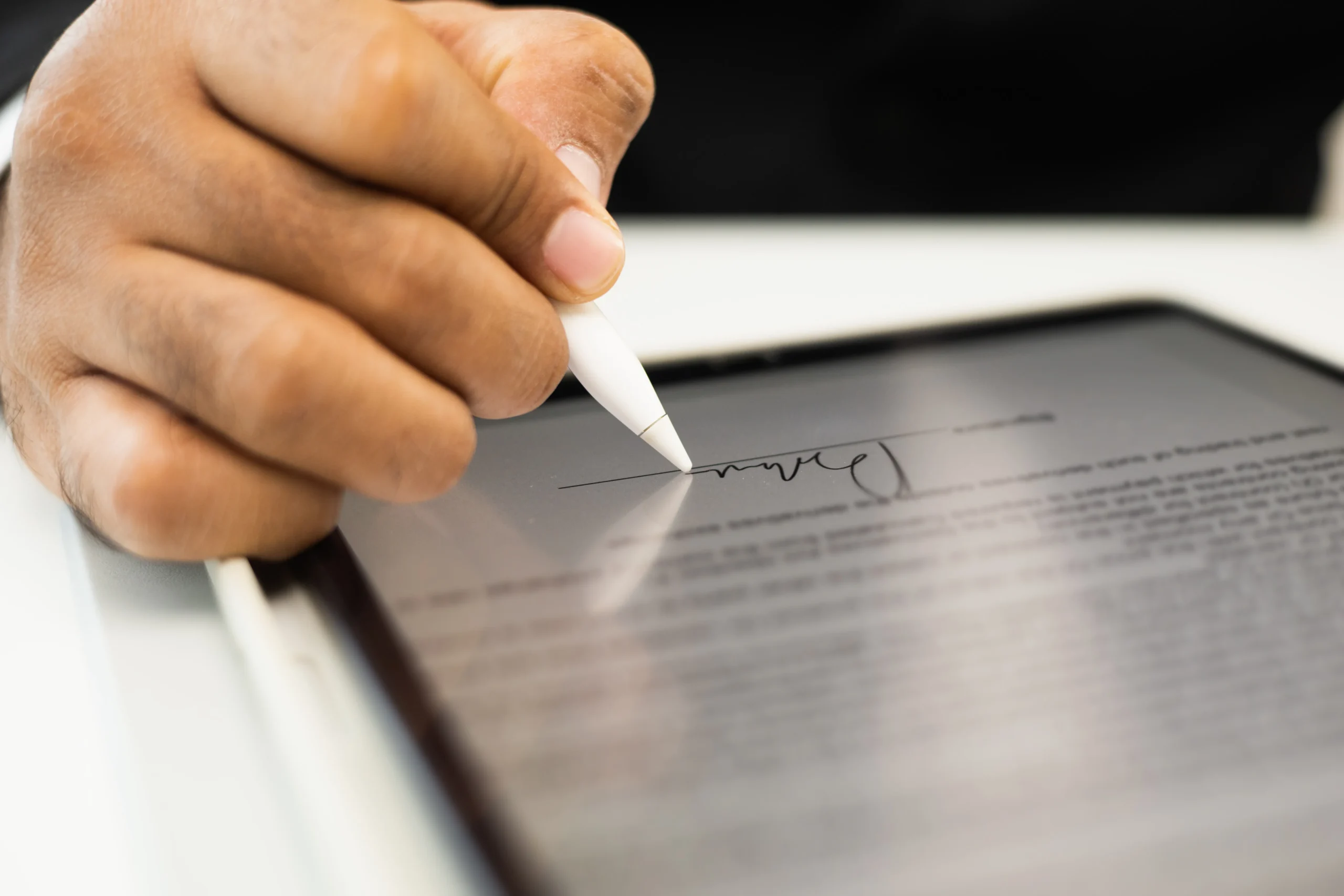 Close-up of a hand signing a contract on a tablet screen with a stylus, representing electronic signature software for sales.