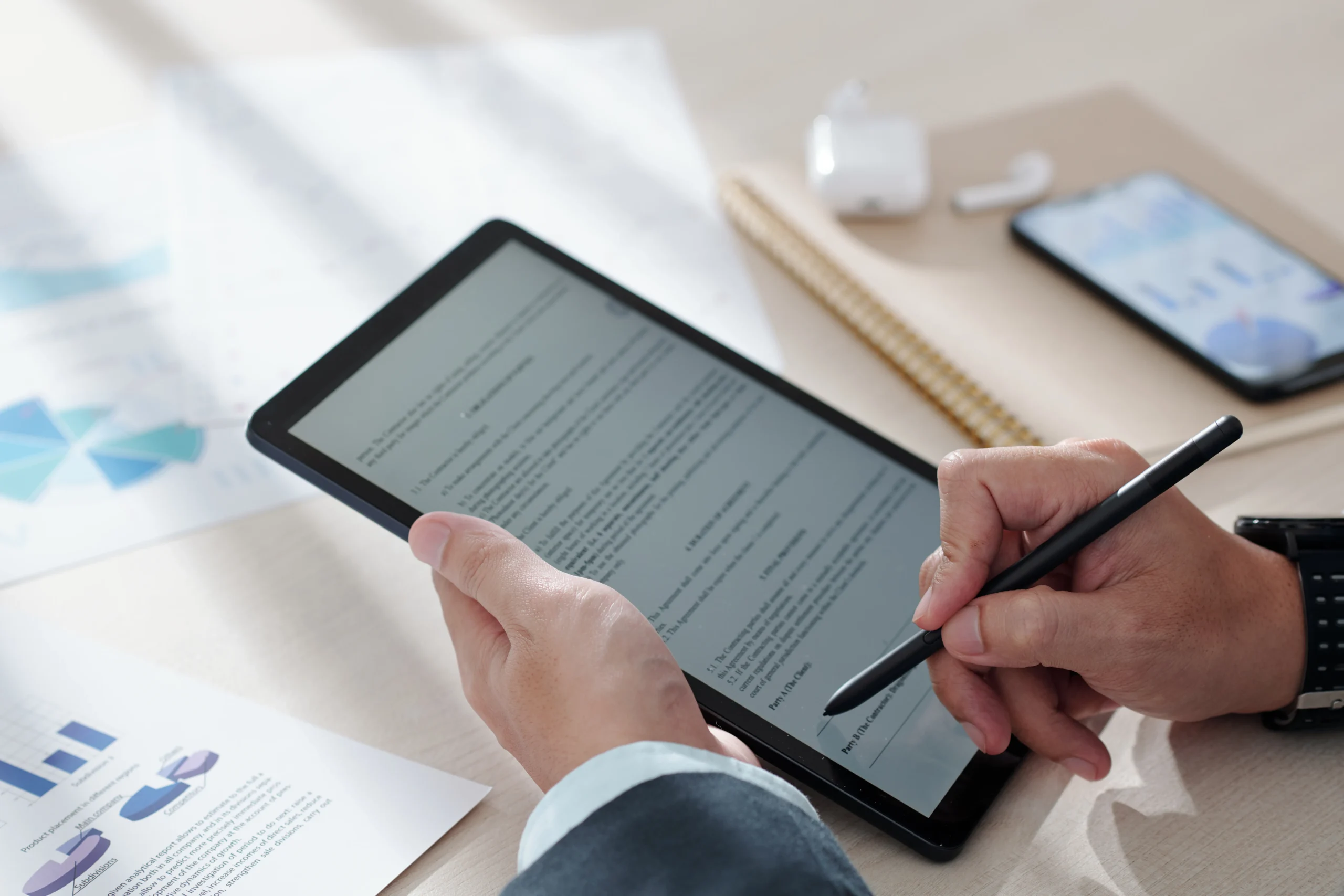 A person holding a tablet and using a stylus pen to digitally sign a contract on the screen, highlighting the user experience of a high-quality eSignature Mobile App.