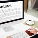 Procurement specialist reviewing a digital contract on a desktop computer screen for procurement contract signing.