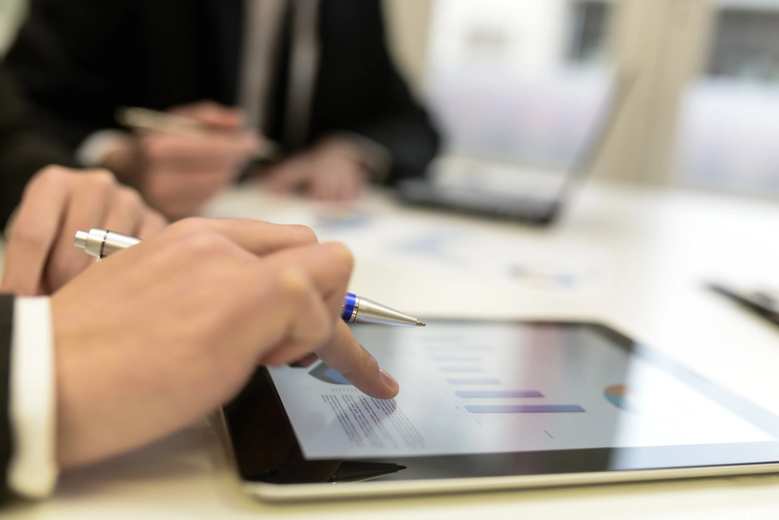 Executive pointing at digital agreement metrics using a tablet with a secure digital signatures interface.