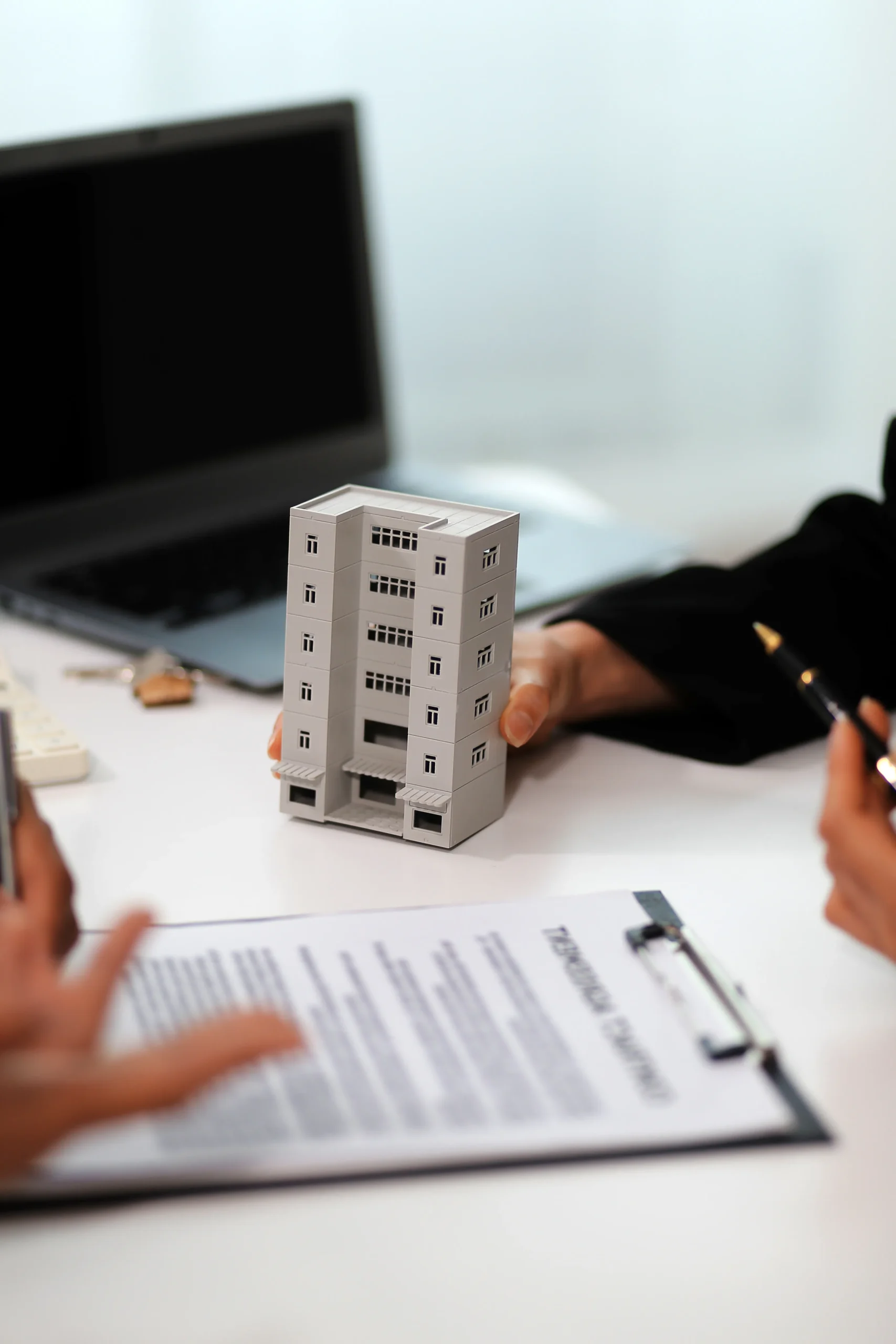 Real estate agent presenting a building model during a meeting for real estate document signing.