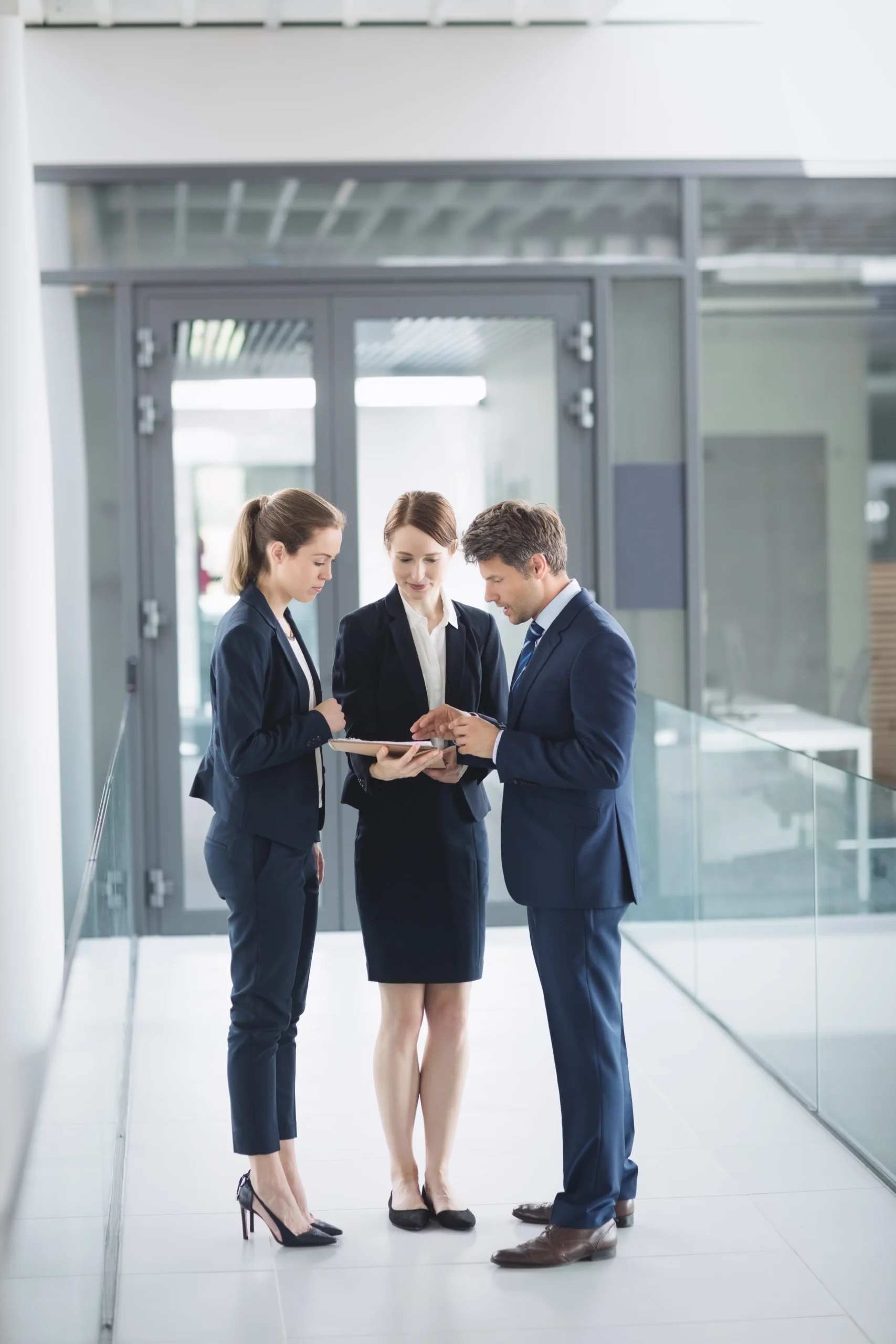 Business executives in suits reviewing documents on a tablet using an eSignature Platform for Procurement.