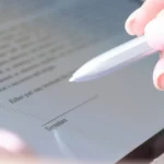 Hand holding a silver stylus over a tablet signature line while testing the best eSignature software for business.