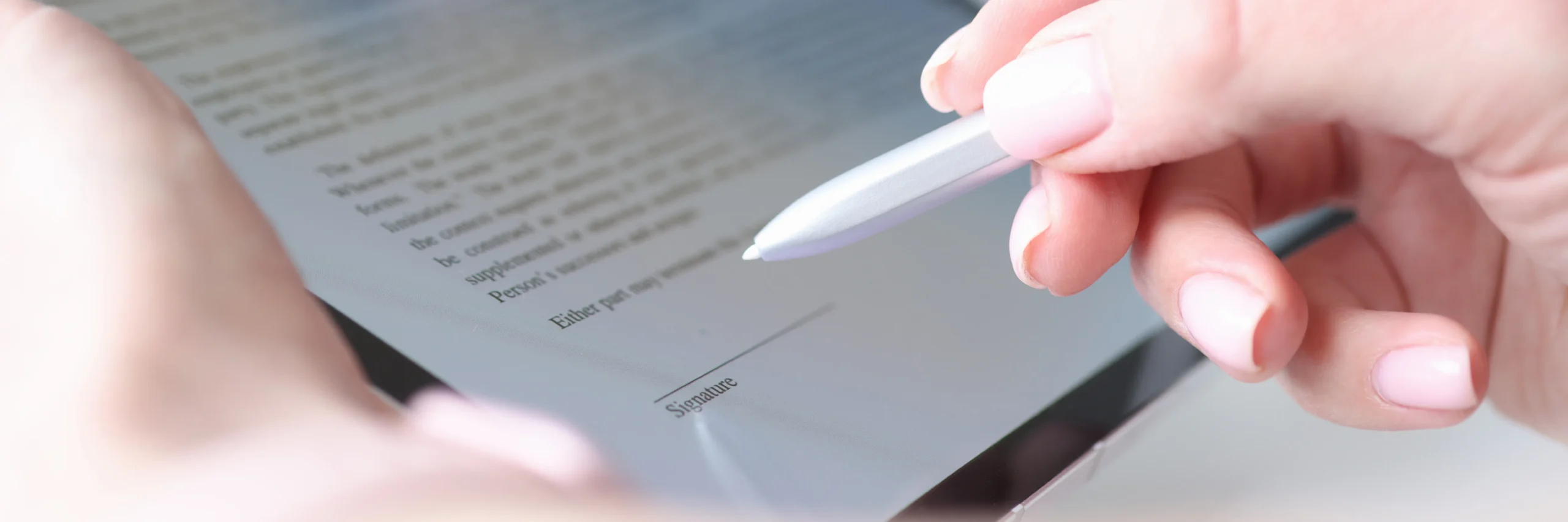 Hand holding a silver stylus over a tablet signature line while testing the best eSignature software for business.