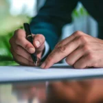 Close up of a professional signing a physical agreement, transitioning workflow to a scalable eSignature platform.