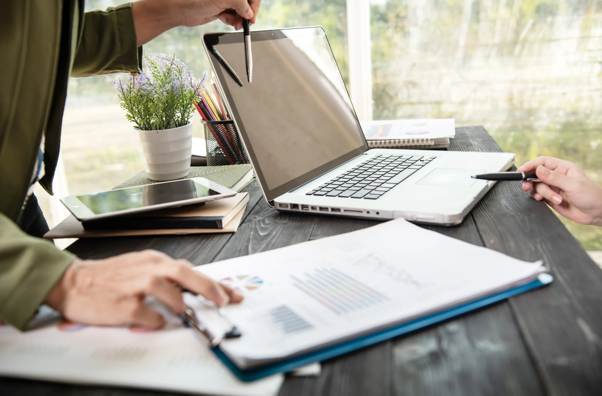 Two professionals reviewing business reports on a laptop using document workflow software.