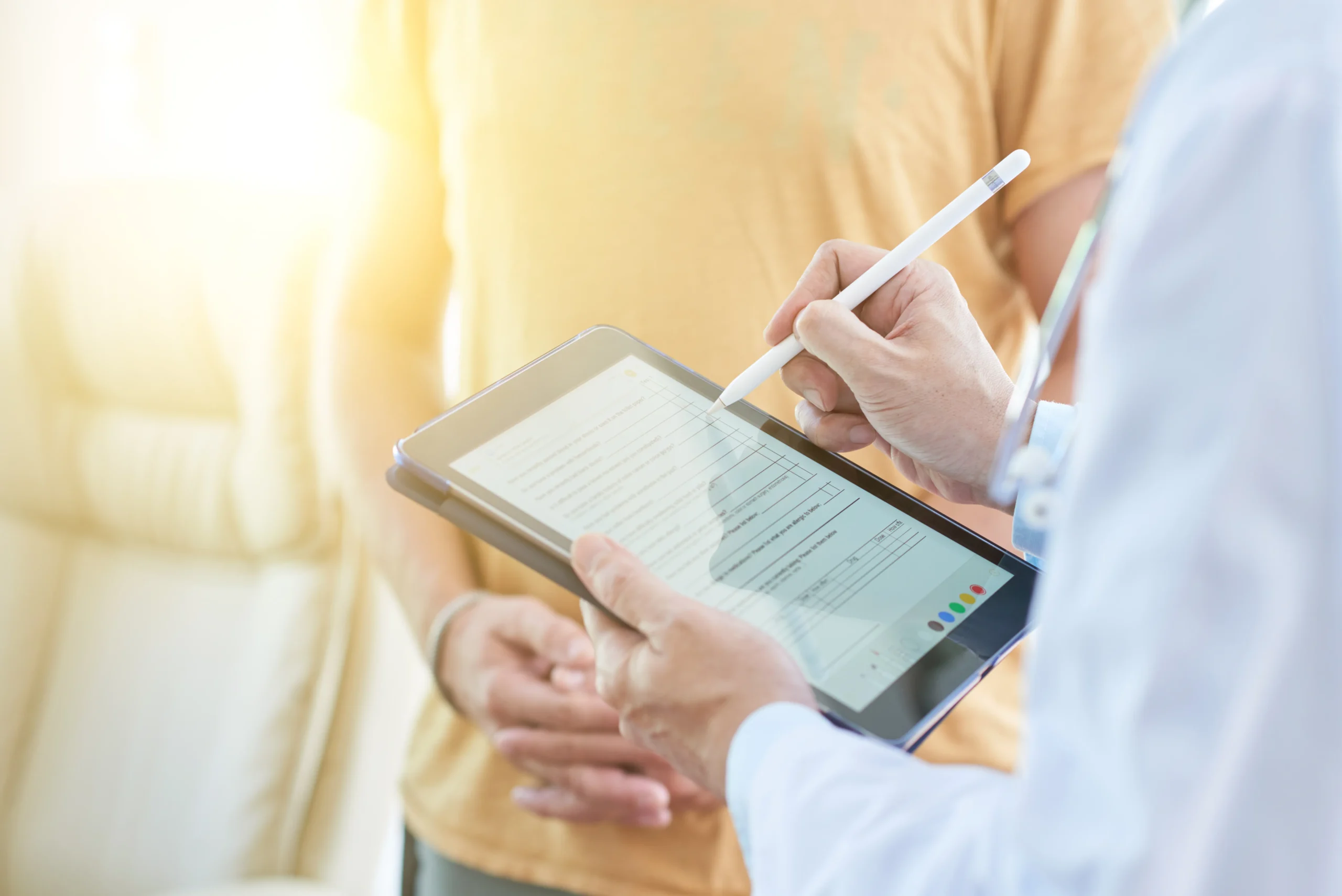 Healthcare provider guiding a patient through completing a patient consent form online using a digital tablet.