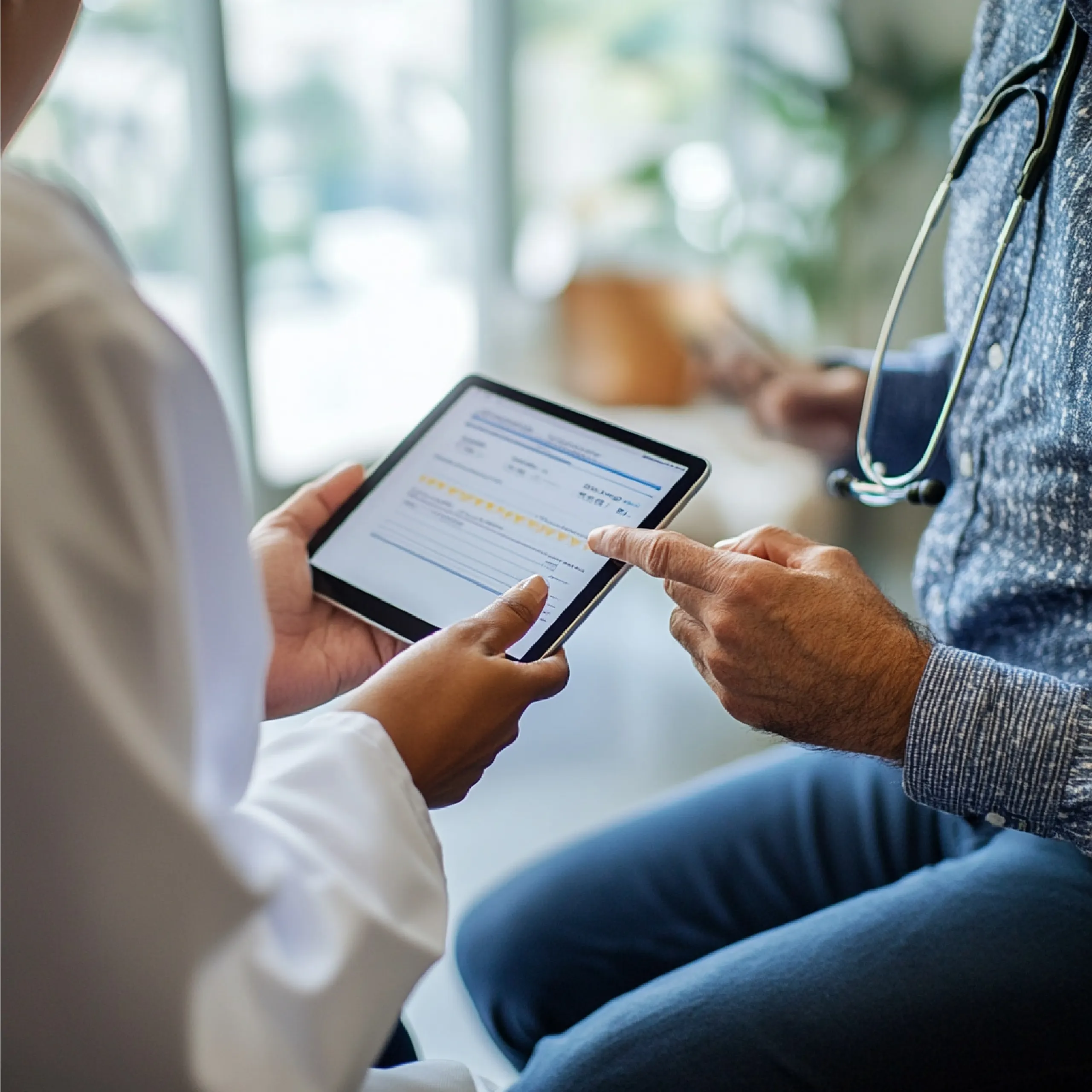 Doctor showing a digital consent form template to a patient on a tablet device during a consultation.